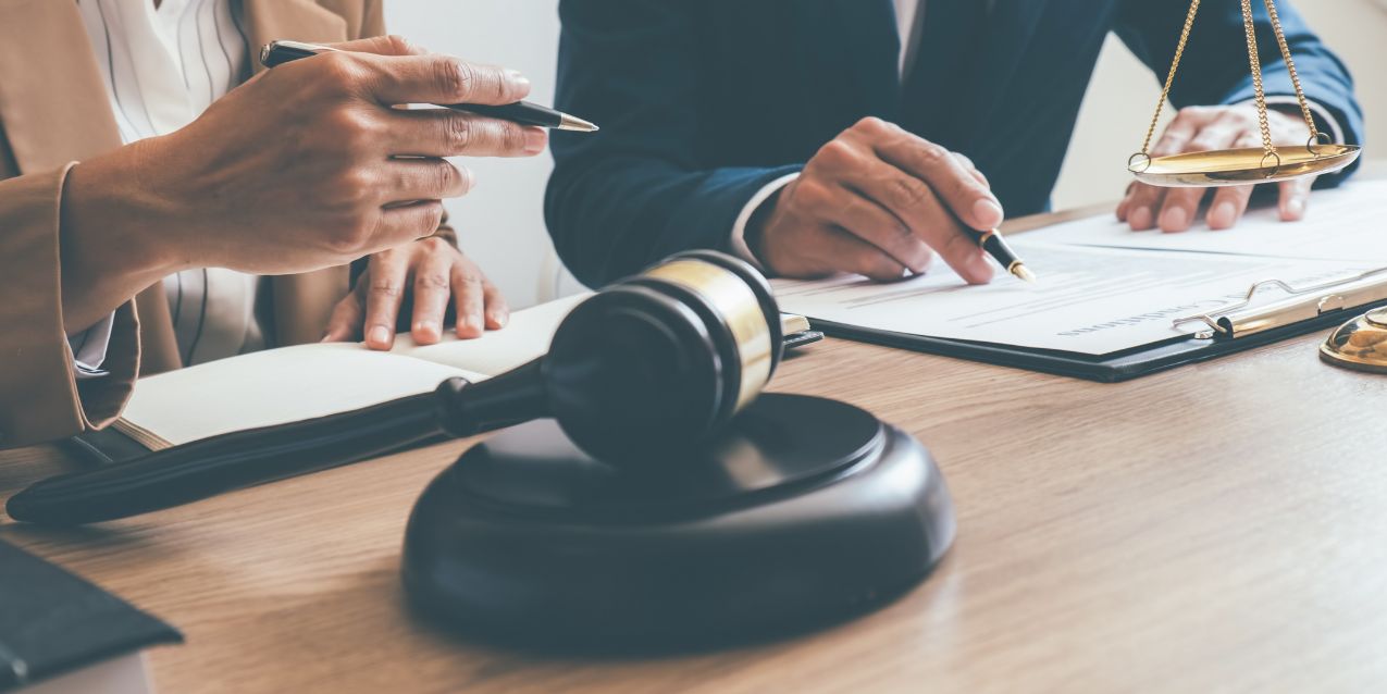 A lawyer and client sit at a table in a courtroom