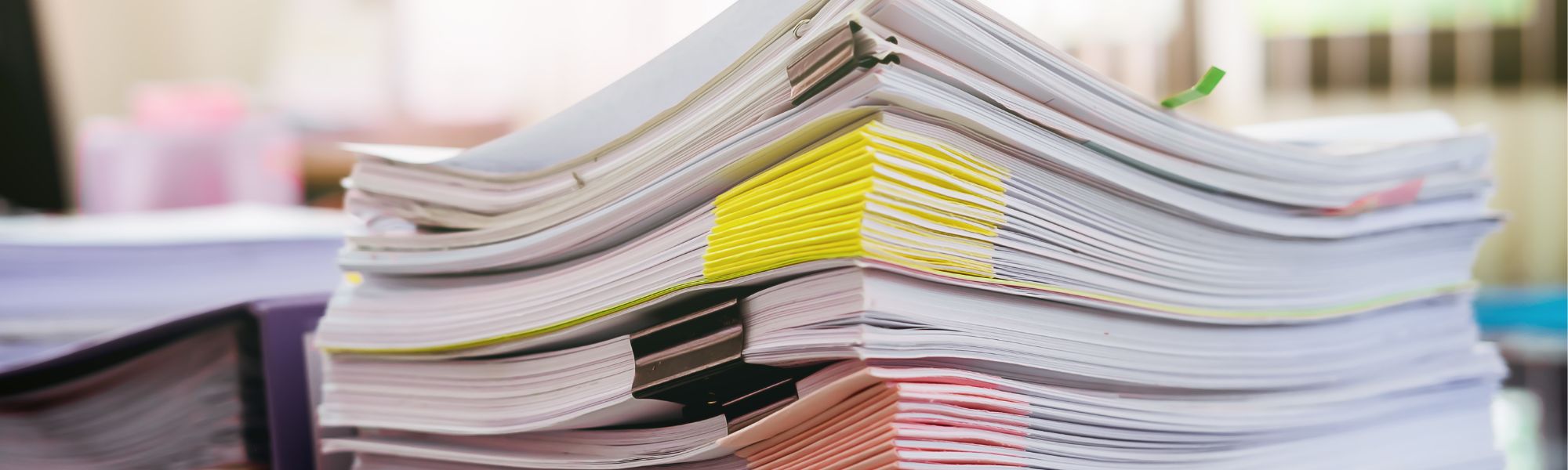 A stack of paperwork and operating agreements sits on top of a desk.